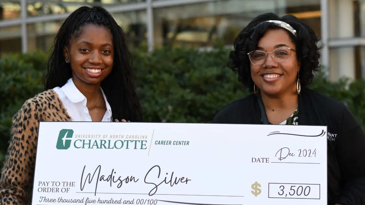 Madison poses with a Novant representative, both holding the $3500 niner career challenge check