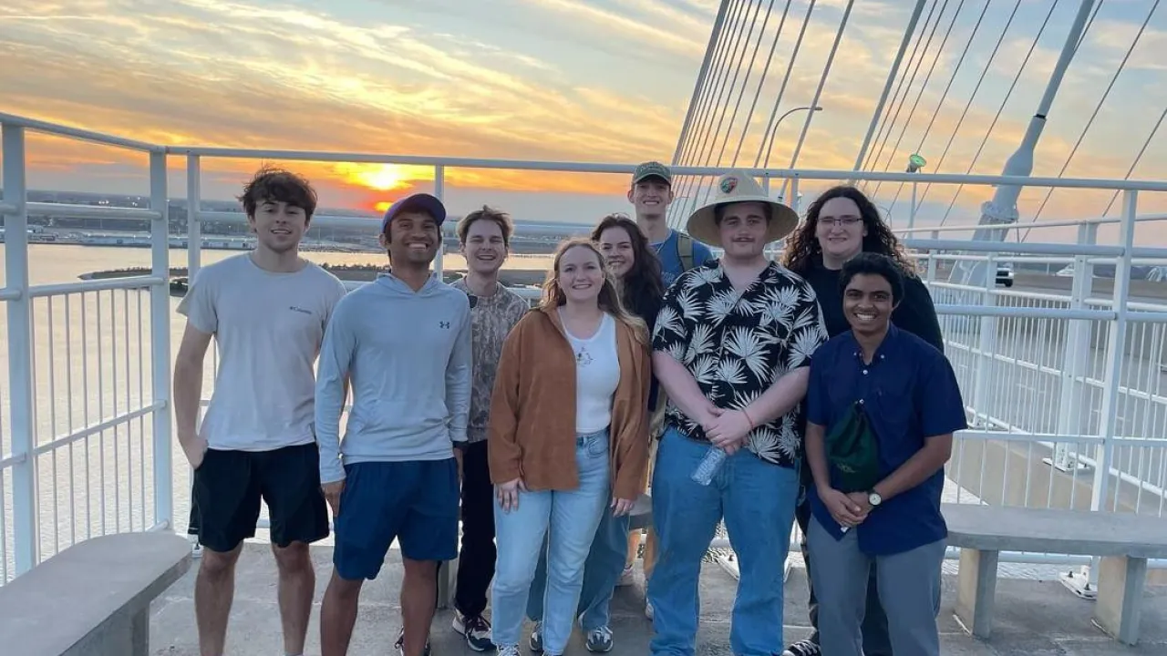 Alternative Service Break students pose on the bridge in Charleston, South Carolina at sunset