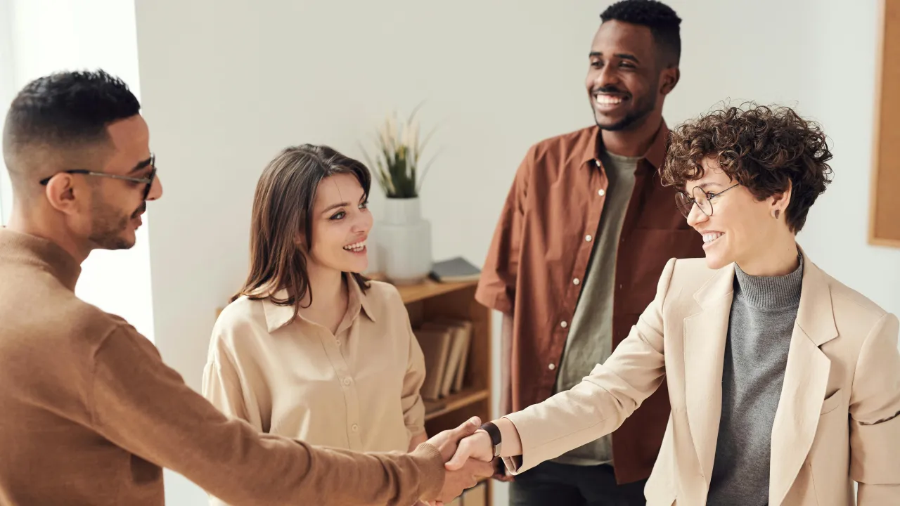 Two people shaking hands while two people watch