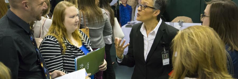 Recruiter at Carer Fair Surrounded by Candidates