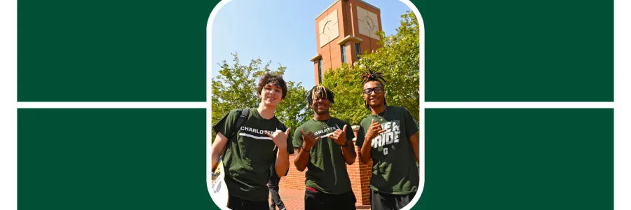 Photo of 3 niners wearing green, smiling down at the camera, holding up the pick axe hand gesture