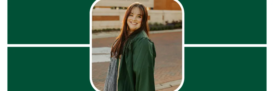 Abbey Burgess poses in her green graduation gown at the main entrance of UNC Charlotte