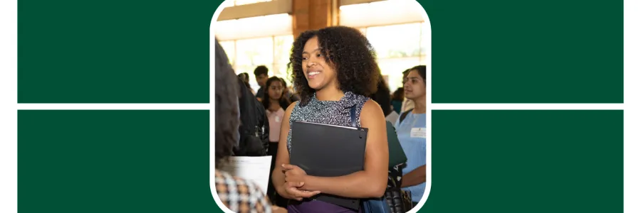 Student smiles while holding a binder at a career fair