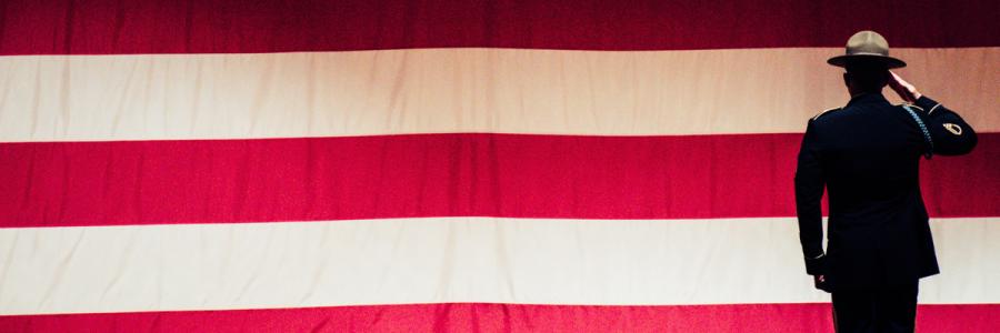 Large American flag backdrop with Marine facing it in shadow