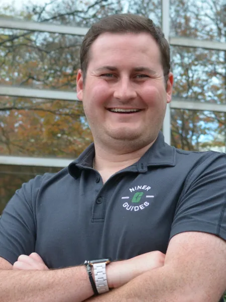 Brady smiles brightly at the camera with his left shoulder turned toward the camera, the background is blurred