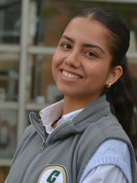 Poornima poses in front of a glass building and some trees