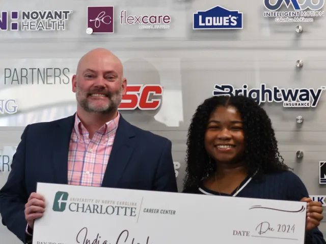 Flexcare representative poses with Niner Career Challenge winner, India, both holding the $3500 check