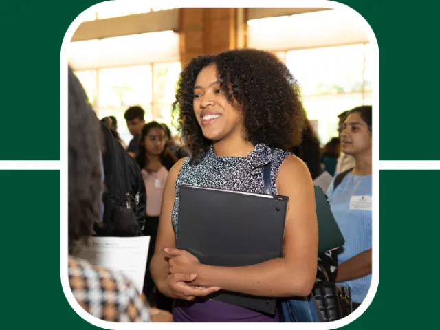 Student smiles while holding a binder at a career fair