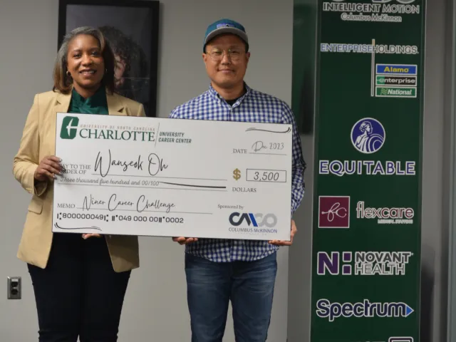 Wanseok Oh poses with the columbus mckinnon employer, they are both holding the large 3500 dollar check he won through the career challenge