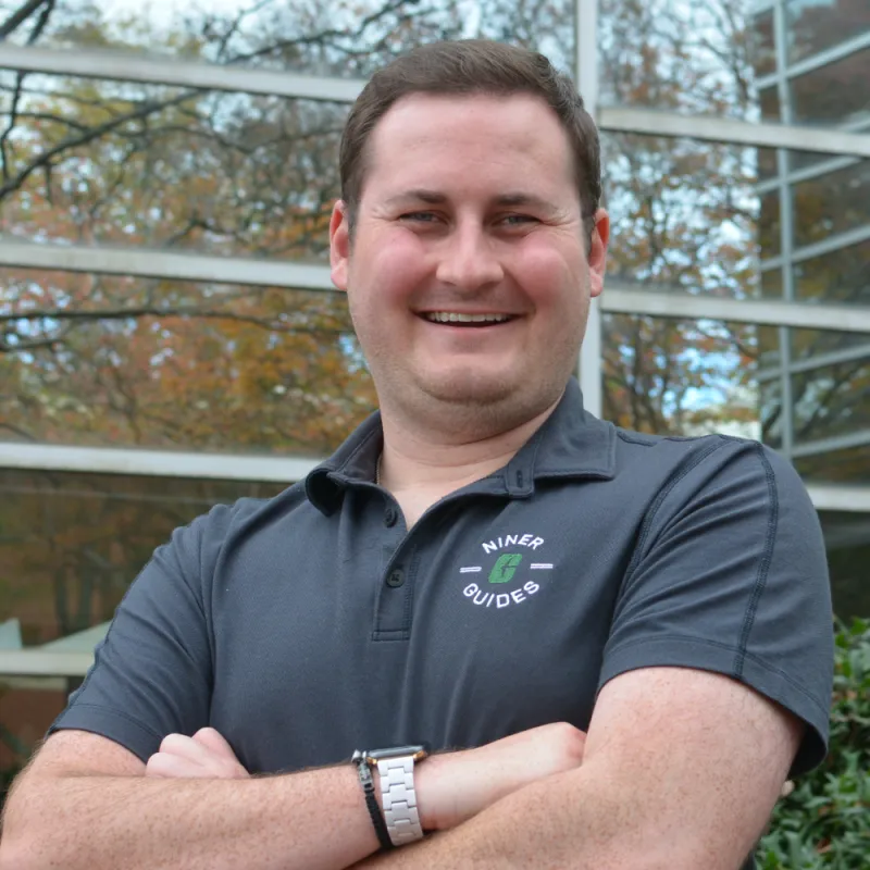 Brady smiles brightly at the camera with his left shoulder turned toward the camera, the background is blurred