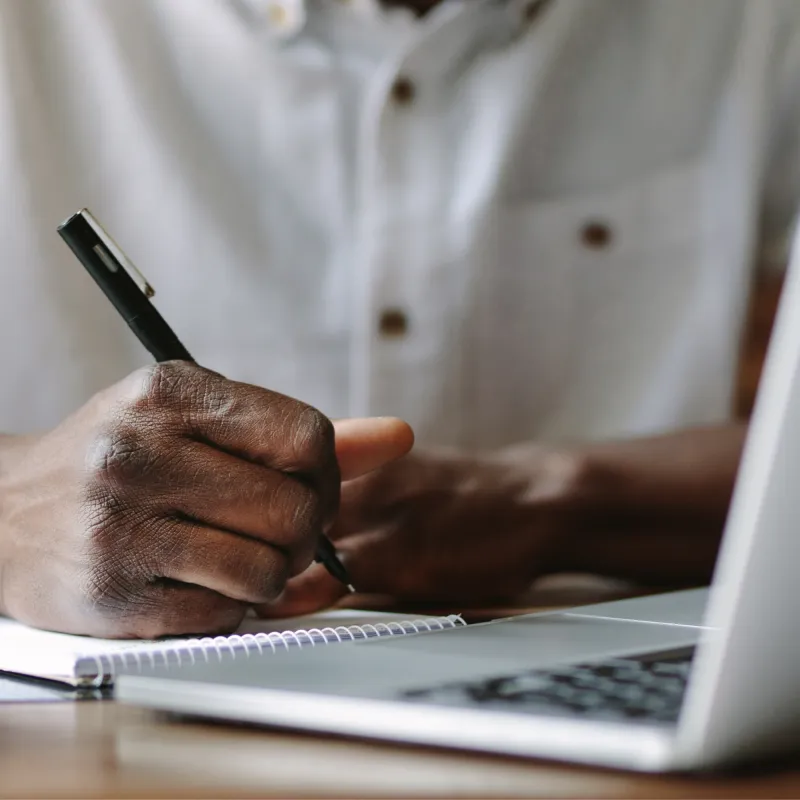 Black person's hand writing on Notepad