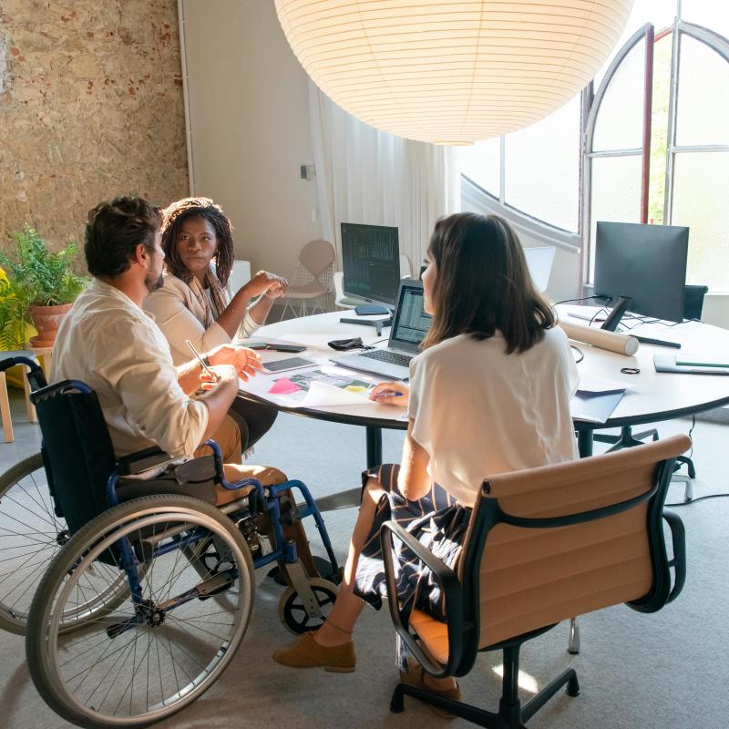 Person in wheel chair with two women seated at a round table